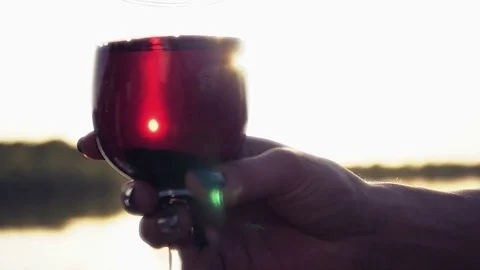 A glass of red wine splashes around the glass in the rays of the sun, catching Stock Footage 76215164