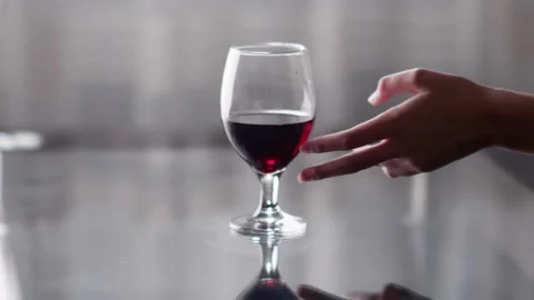 A glass of red wine stands on the table, a woman's hand takes a glass Stock Footage 137415567