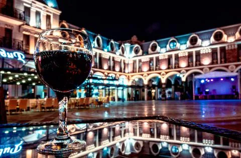 Glass of red wine on a table with reflection in a cafe on an empty Piazza squ Stock Photos