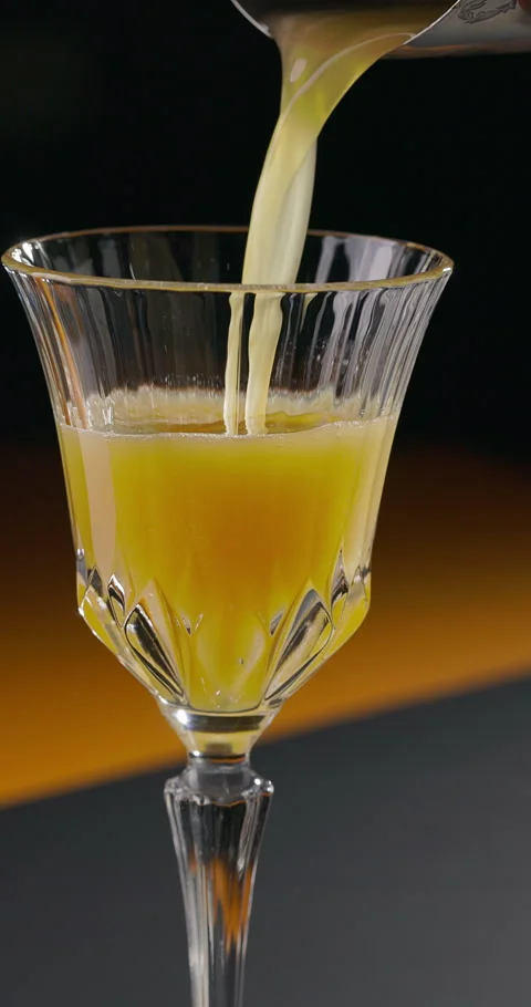 Glass of refreshing orange cocktail. Bartender pouring cocktail from shaker Stock Footage 308413334