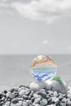 Glass round ball on the beach reflects the sea in summer Stock Photos