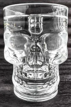 A glass with the shape of a skull on a dark background. Stock Photos
