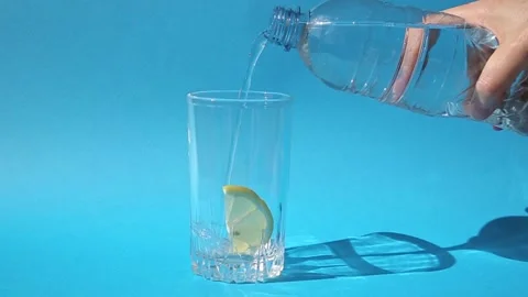 A glass with a slice of lemon , into which drinking water is poured Stock Footage 165323782
