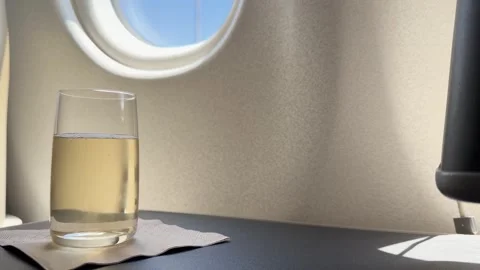 Glass of Sparkling Champagne on a First Class Airplane Table Stock Footage 329349935