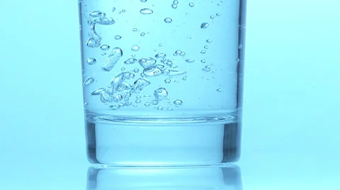 Glass of Sparkling Water against Blue Background, Slow Motion Stock Footage