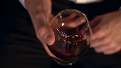 The glass with splashes cognac, slow motion. Glass of cognac in the man's hand. Stock Footage 72723841