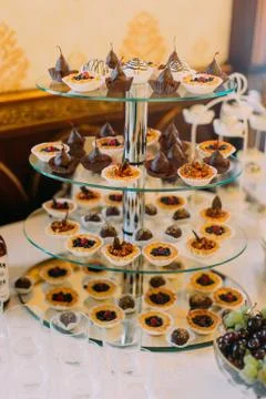 The glass stand covered with differen wedding cupcakes. Stock Photos