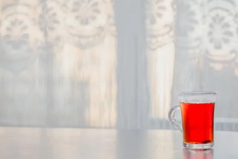 A glass of steaming hot tea on the table against the window Фото