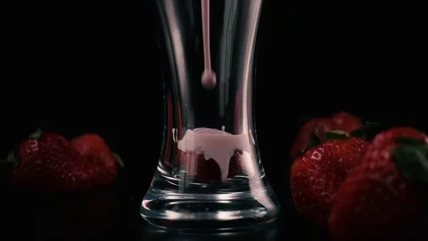 In a glass with strawberries pour a milkshake. Slow mo Stock Footage