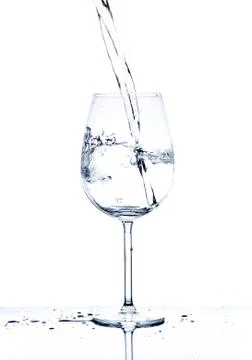 Glass with the stream of dinking water Stock Photos