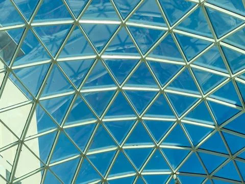 Glass structure shows geometric pattern with clear blue sky visible above Stock Photos