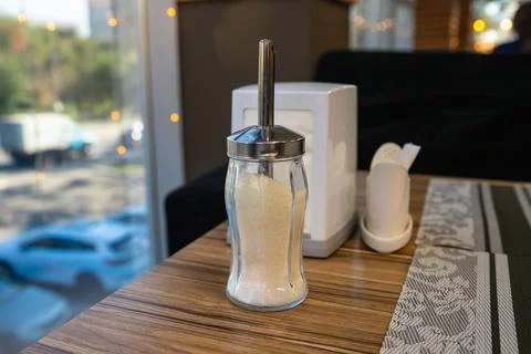 Glass sugar container placed on a table in a modern cafe setting during day Stock Photos