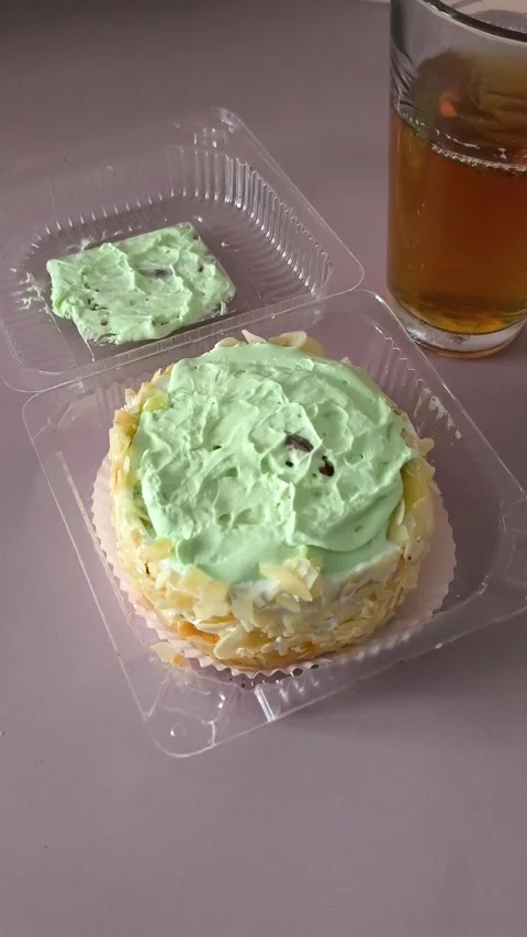 A glass of tea and a transparent plastic container with a pie with cream and Stock Footage 324698323