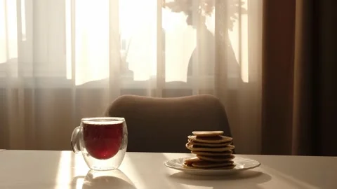 Glass with tea steaming on table with few pancakes in the morning Stock Footage 159548040