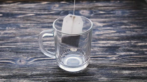 Glass of tea with teabag and pouring water in slowmotion Stock Footage 59190148