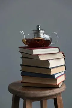 Glass teapot filled with tea on a stack of books Fotos de archivo