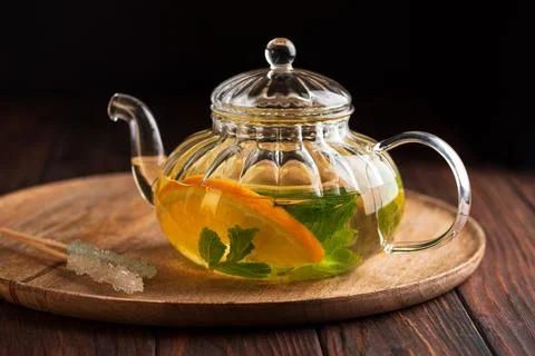 Glass teapot infusing herbal tea with orange and mint Stock Photos