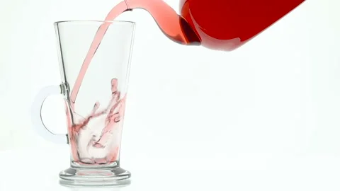Glass teapot pouring fruit tea into cup on white background Stock Footage 96992033
