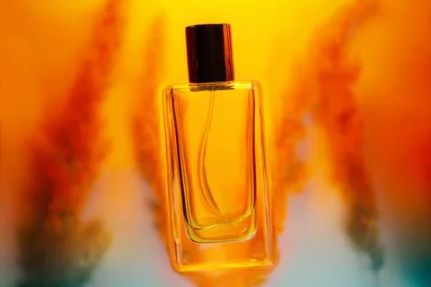 Glass transparent rectangular perfume bottle on a golden background with a .. Fotos de archivo