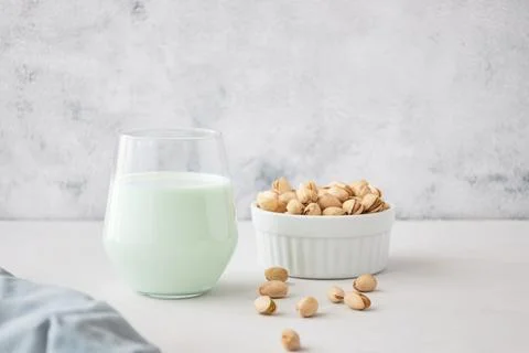 A glass of vegetable milk from nuts on the table next to pistachios. The perfect Stock Photos