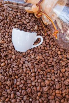 Glass vessel and coffee mug on pile of coffee beans. Background. Stock Photos