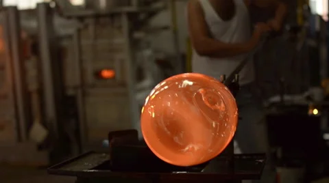 Glass virtuoso craftsman blowing hot molten glass with pipe Stock Footage