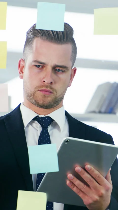 Glass wall, sticky notes and tablet with business man in office for Stock Footage 323526309