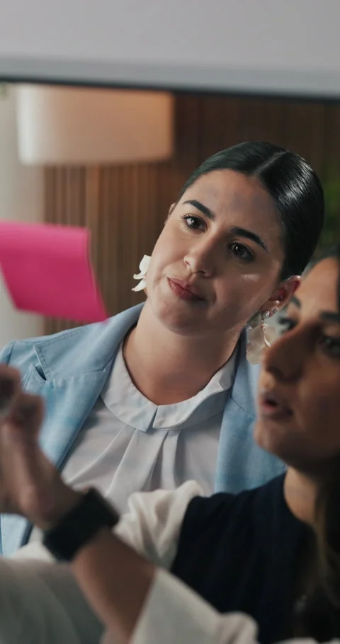 Glass wall, sticky notes and talking with designer women in office for Stock Footage 331054968