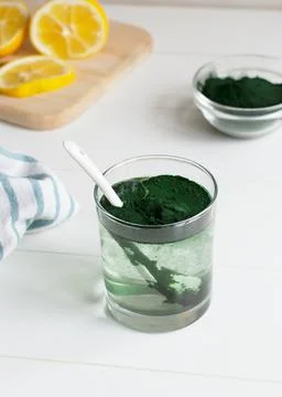 A glass of water and spirulina on the table. Healthy food concept.  Stock Photos