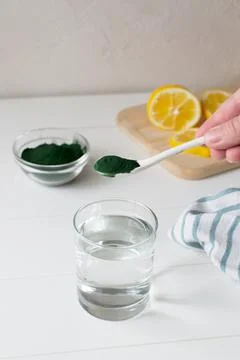 A glass of water and a teaspoon of spirulina in your home kitchen.  Stock Photos