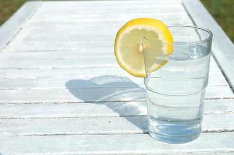 Glass of water decorated with lemon slice on table Stock Photos