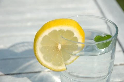 Glass of water decorated with lemon slice and peppermint leaf Stock Photos