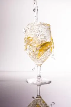 Glass of water with fresh lemons, splashing water drops Stock Photos
