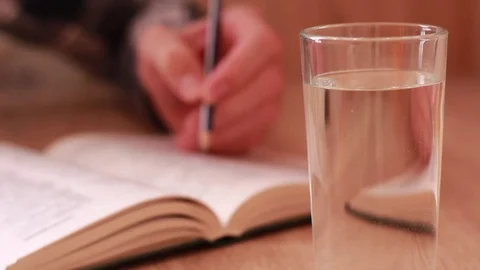 Glass of water in front of the opened book. Reading 動画素材 84676093