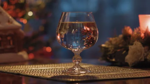 A glass of water stands against the background of an evening window Stock Footage