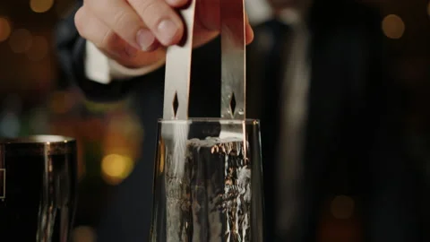 Glass in which the bartender puts a piece of ice on the dark background Stock Footage 219113986