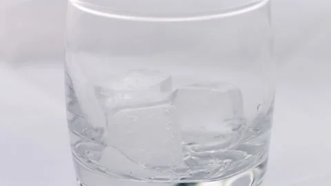 Glass of whiskey with ice cube. Stockbeeldmateriaal 239228661