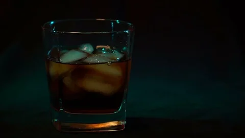 Glass whiskey with ice cubes on the bottom, slow motion Stock Footage 99157461