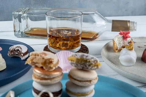 Glass of whiskey with ice surrounded by assorted wedding candies. In the blur Stock Photos