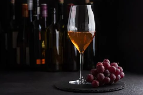 Glass of white wine with bunch of grapes on dark slate background Foto stock