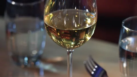Glass of white wine is shaking on the table in restaurant Vídeos de archivo 219530777