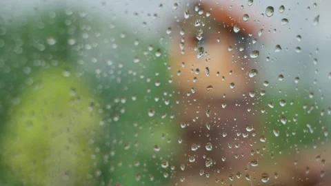 Glass window with rain drops on surface during rainy day with blurry background Video stock 308668600