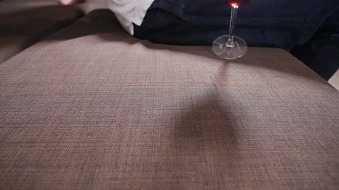 A glass of wine falls on the sofa and spills wine. Stock Footage 101008445