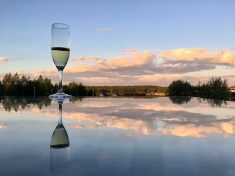 A glass of wine reflected in the mirror surface of the table Stock Photos