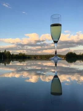 A glass of wine reflected in the mirror surface of the table Stock Photos