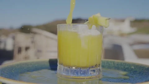 A glass of yellow liquid with a slice of lemon in it is on a blue plate Stock Footage 306576761
