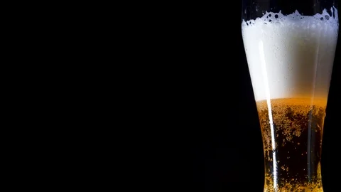 A glass with a yellow liquid in which bubbles of air and white foam Stock Footage 105668595