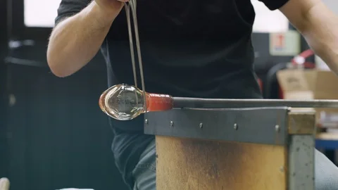 Glassblower blowing pipe while shaping glass Video stock 107891136
