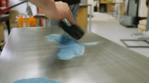Glassblower cleaning sand from table Stock Footage 107920531
