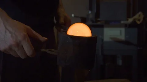 Glassblower in his workshop and rotating rod with liquid glass. Close-up. Stock Footage 109716586